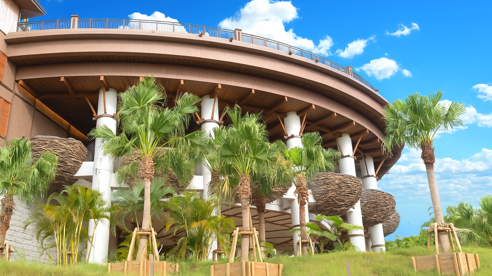 ジャングリア沖縄のインフィニティ・テラス。円形の大屋根と白い柱、鳥の巣のような装飾に囲まれ、南国のヤシの木が植えられている。